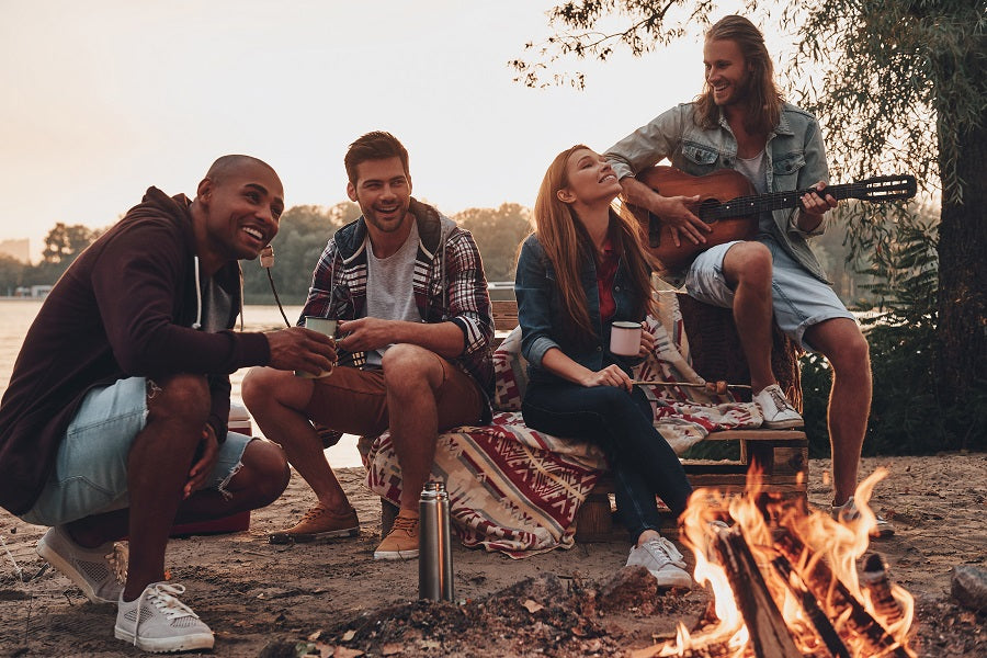 A group of friends playing music around a campfire.