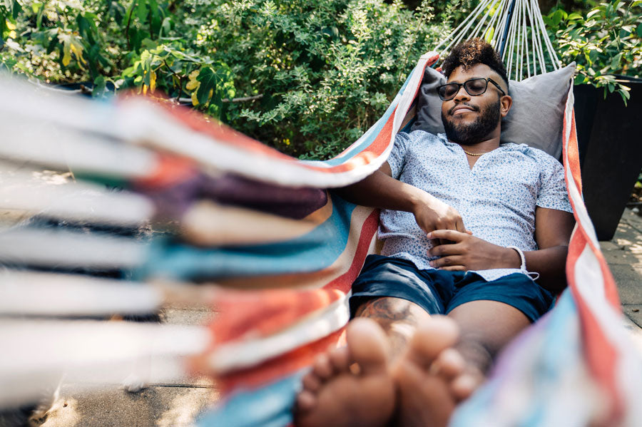 A man wearing sunglasses resting in a hammock.