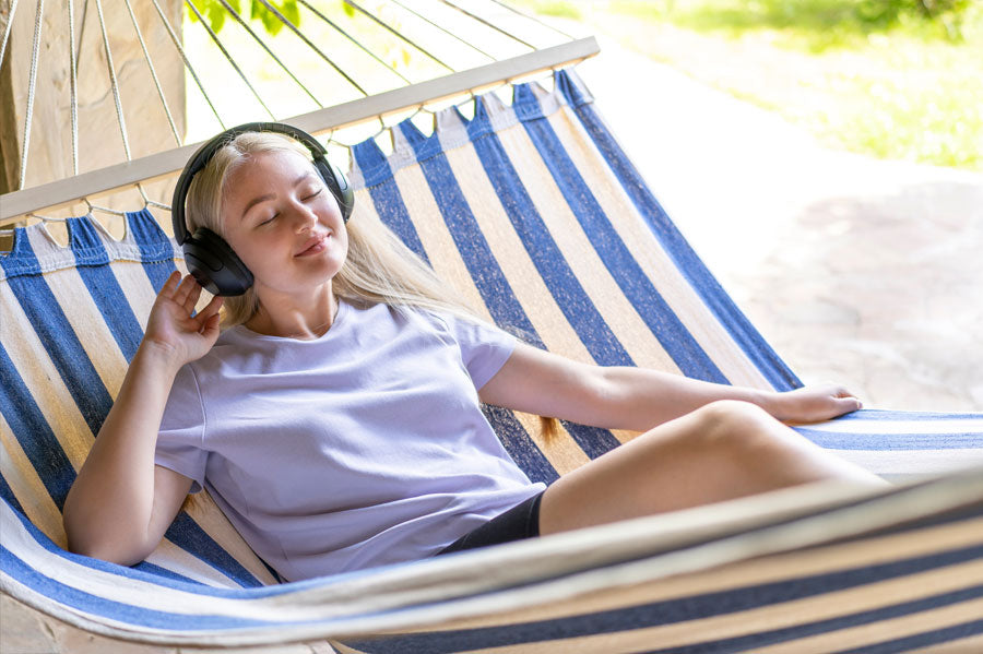 Young Women relaxing in a hammock listening to music with her black headphones