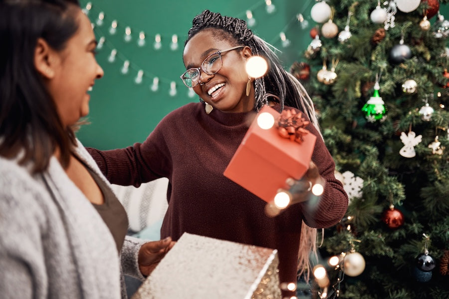 Shot of two happy young women exchanging gifts during Christmas at home.