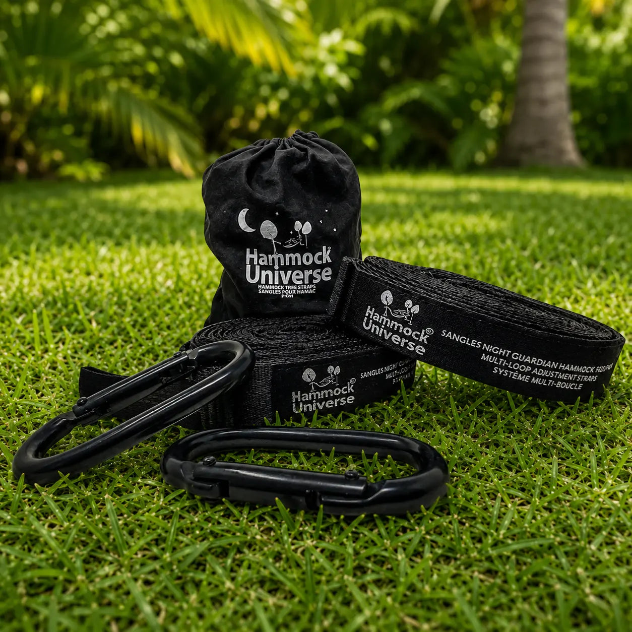 Black hammock accessories including straps and carabiners on grass with 'Hammock Universe' branding.