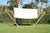 A standing hammock being moved by the wind in a sunny backyard.