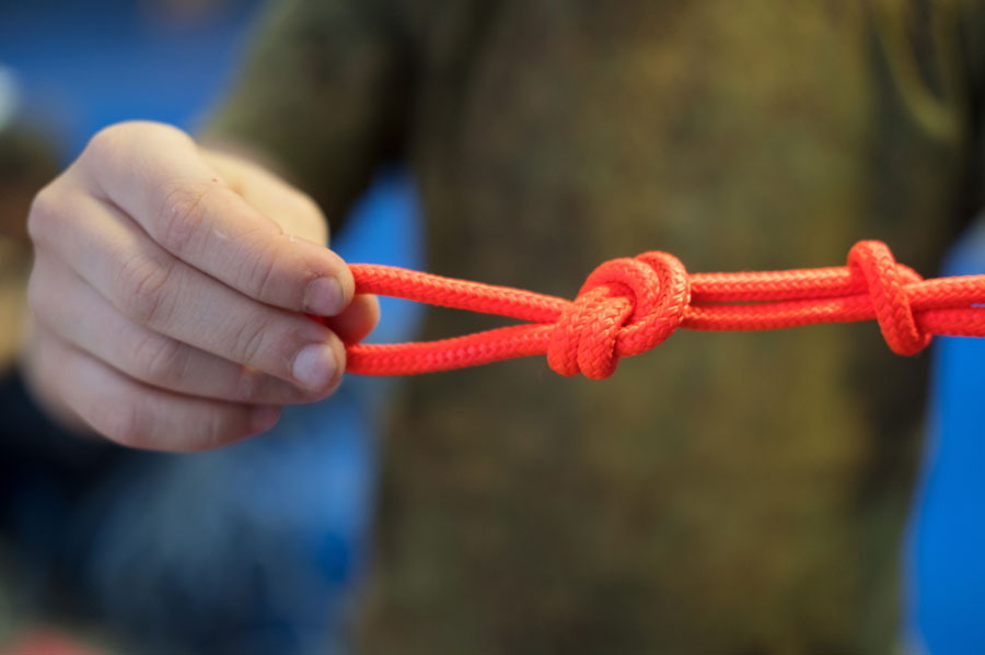 A person holding a red rope tied in two knots.