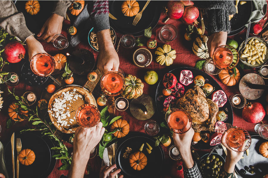 People toasting glasses at a well decorated table for thanksgiving.