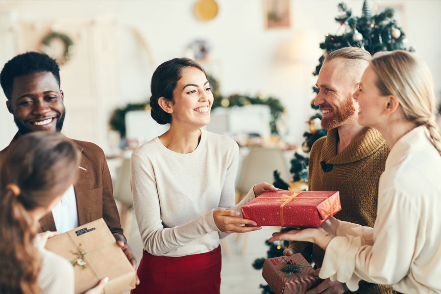 A group of friends smiling and exchanging gifts.