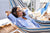 Women smiling and relaxing in the hammock as part of the the slef care routine. In the background her husband is following her lead of self care 