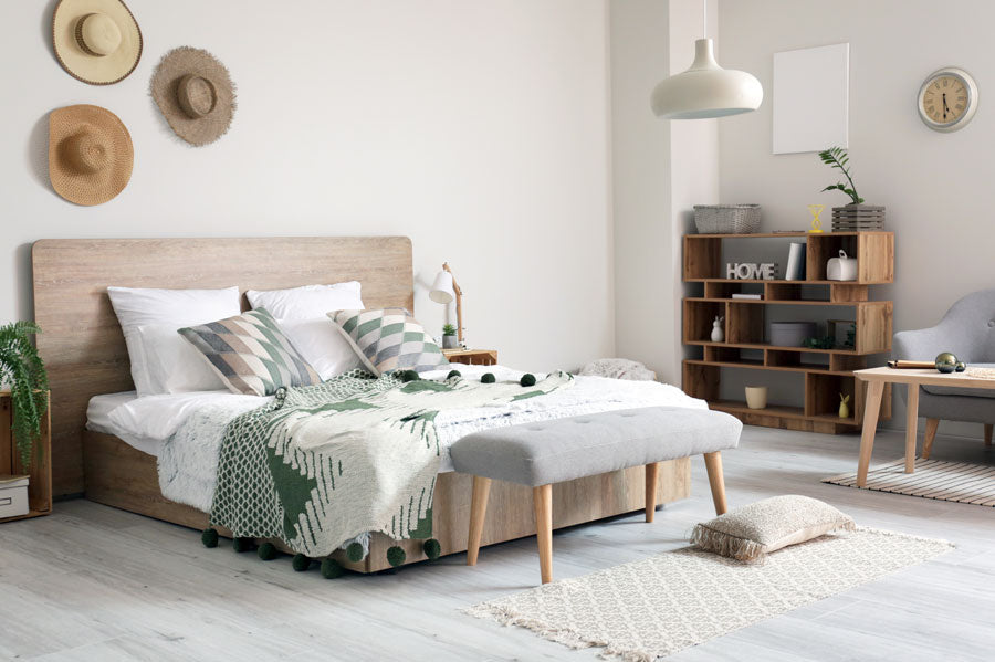 A modern bedroom with a large bed with white and green blankets.