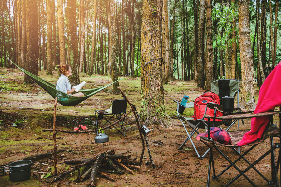 Women sitting in the hammock with a book in her hands enjoy her time in the great outdoors.
