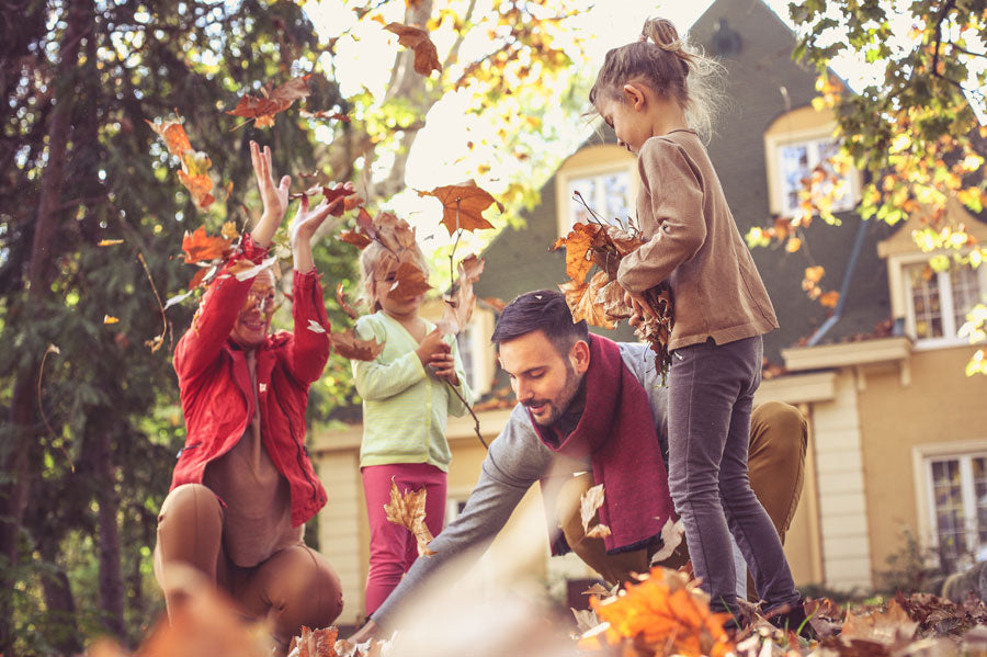 A family playing in fallen leaves in autumn.