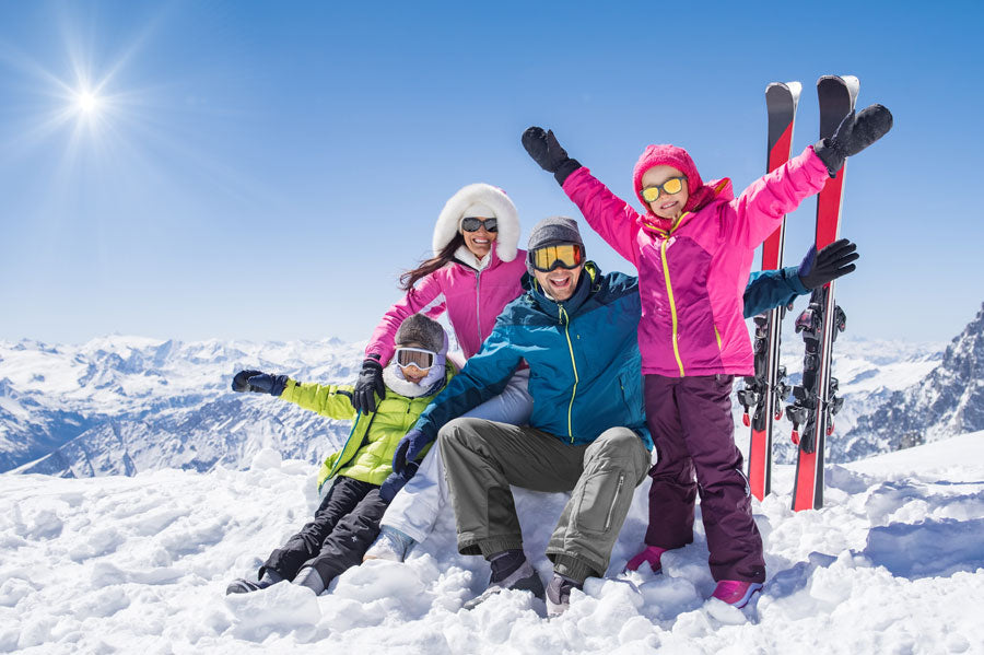 Parents and their two children posing for a photo on a snowy mountain.