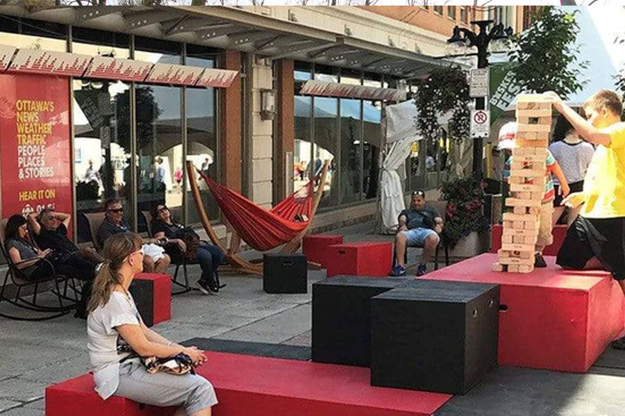 Sparks Street event where people are enjoying the sunny playing giant jenga and sitting on bench and hammock.
