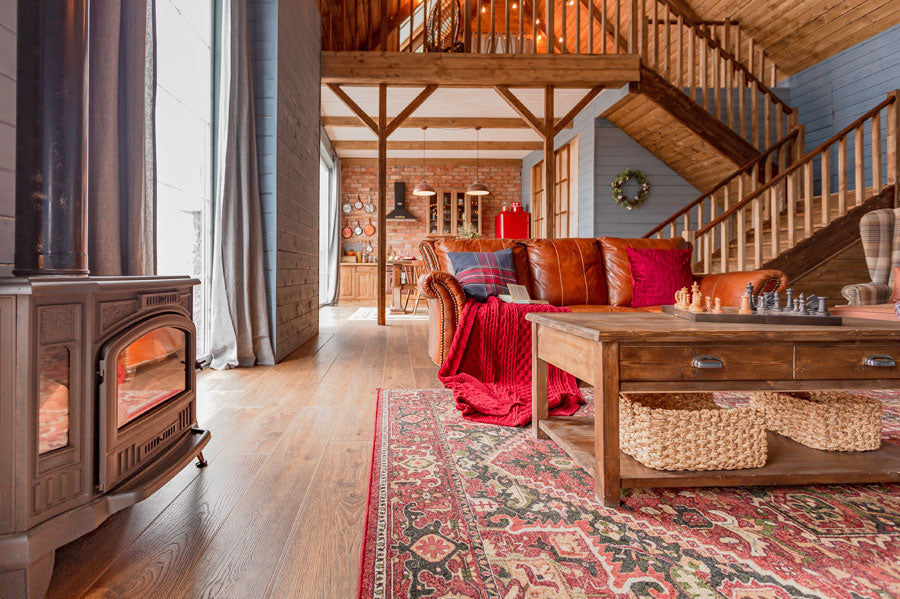 A cozy cottage living room with a fireplace, red couch and coffee table.