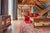 A cozy cottage living room with a fireplace, red couch and coffee table.