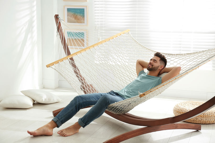 A man relaxing on his indoor hammock feeling peaceful and relaxed