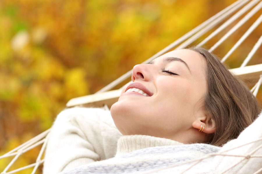 Closeup of a smiling woman with her eyes closed in a hammock.
