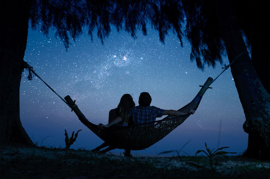 Couple sitting in the hammock and stargazing the night sky