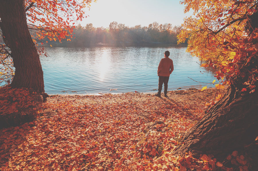 A person standing near the lake in autumn.