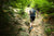 A man running in a rocky trail in a forest.