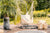 Hammock chair hanging on a spacious backyard deck, surrounded by lush greenery and a peaceful outdoor setting.