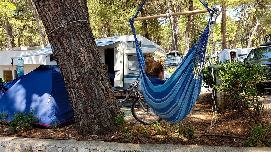 A woman in a hanging chair in a campsite.