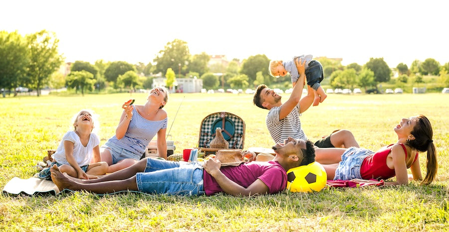 a family outdoors, relaxing on the grass, playing 