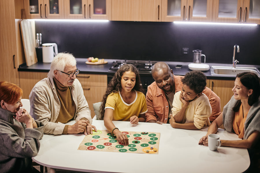 A family playing a board game in a kitchen.