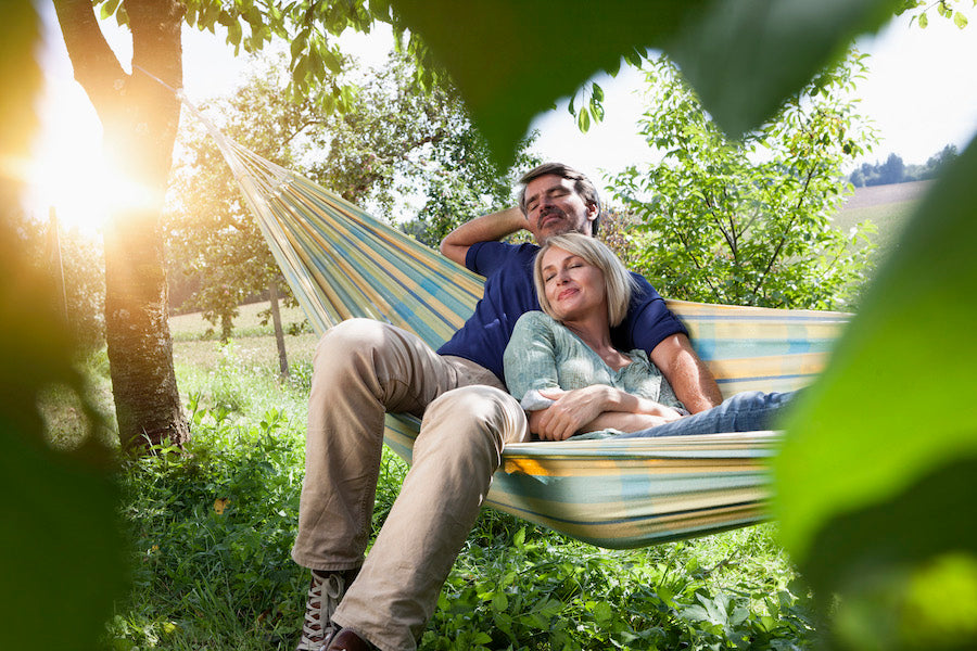Older couple resting in a hammock together in a feild.