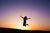The silhouette of a woman jumping for joy at sunset.