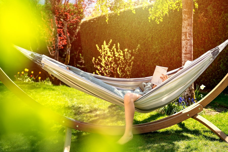 a person reading in a hammock in their beautiful backyard