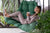 A woman resting and holding a mug on a green hammock chair on a porch.