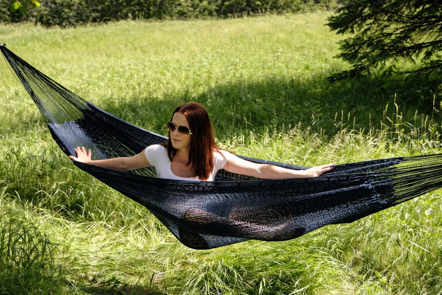 Woman relaxing in a black hammock in a grassy field #24-MHXLTC-FG