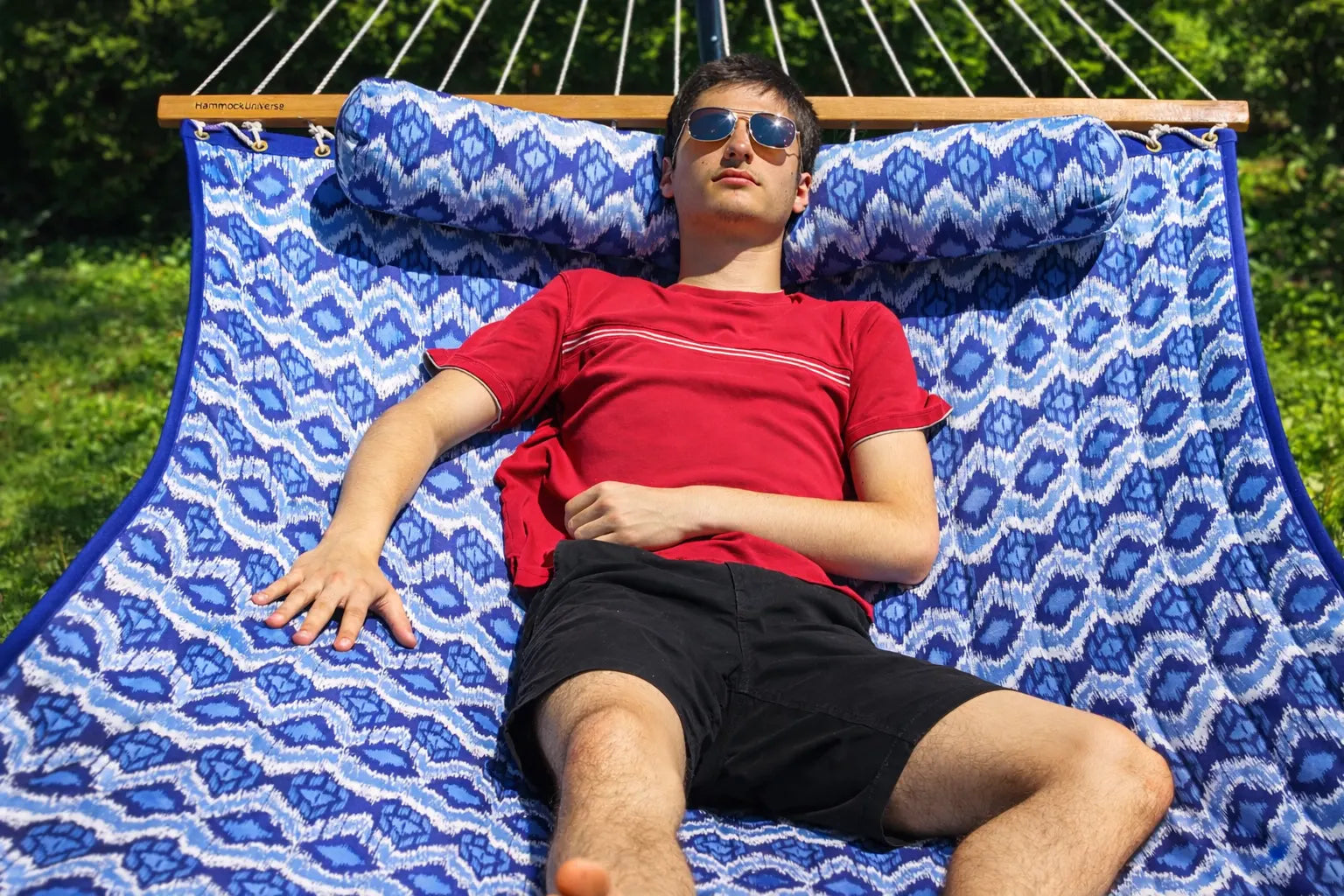 Man lying on a blue patterned hammock outdoors QHD-BWP+15TBSB