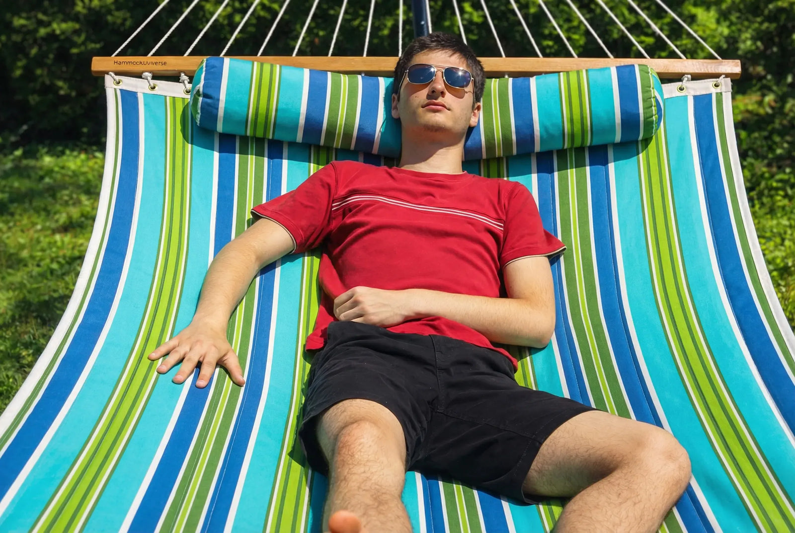 Person relaxing on a colorful striped hammock outdoors  