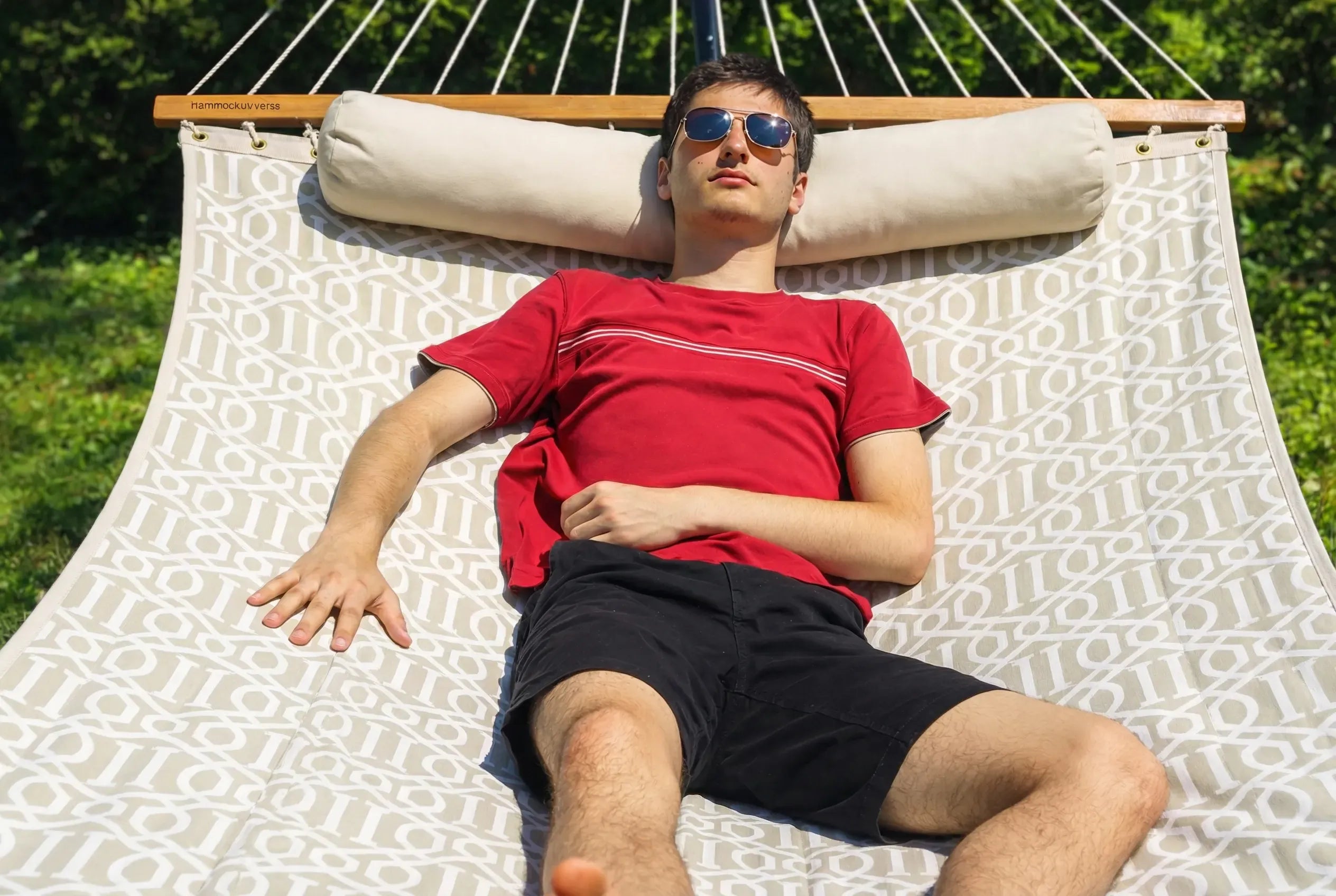 Man wearing sunglasses lying on a hammock with a patterned cushion  QHD-COUNTRY