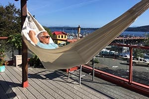 man resting in the sun in a colombian white hammock by the sea