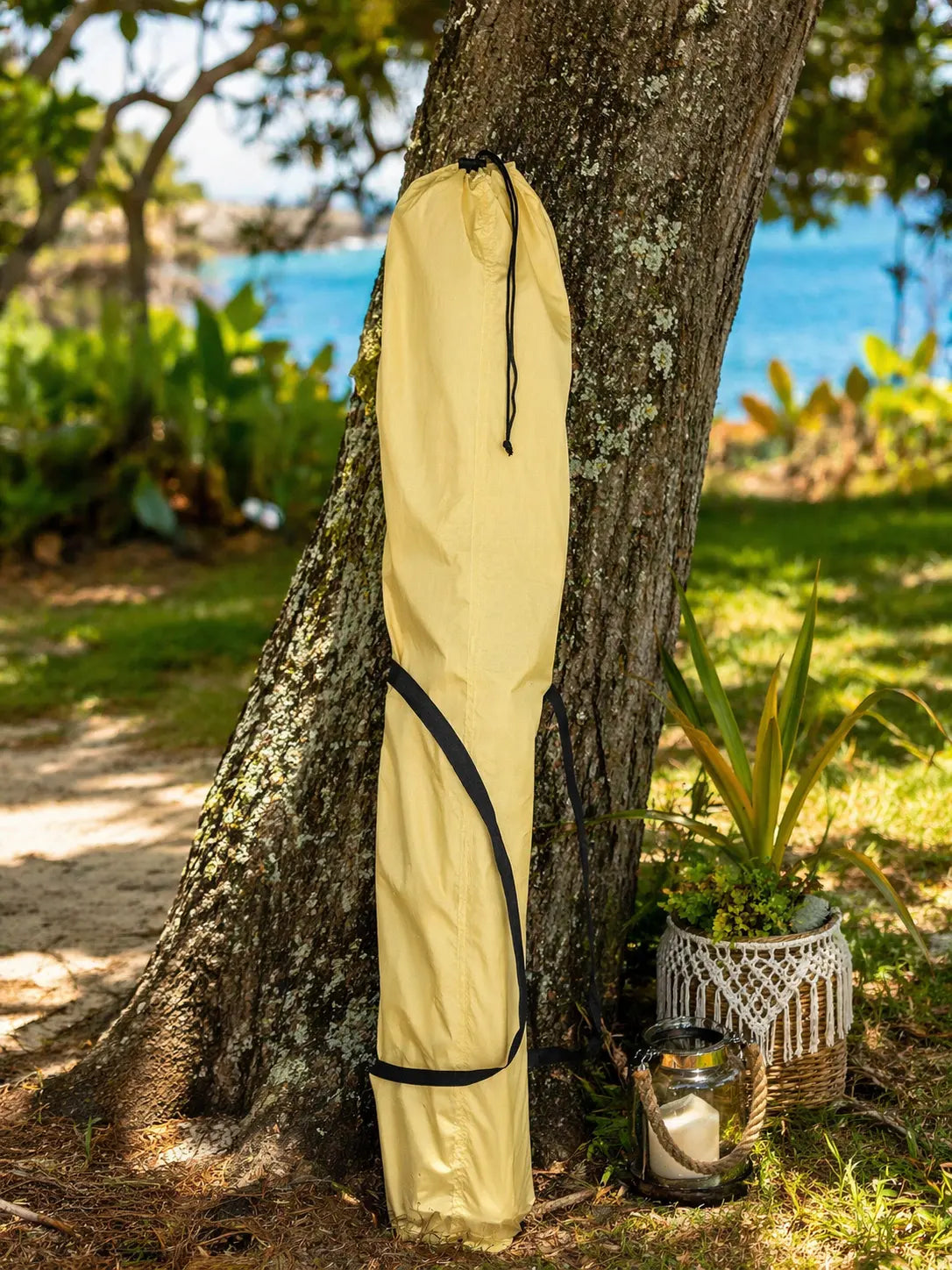 Beige fabric roll tied to a tree with a scenic background